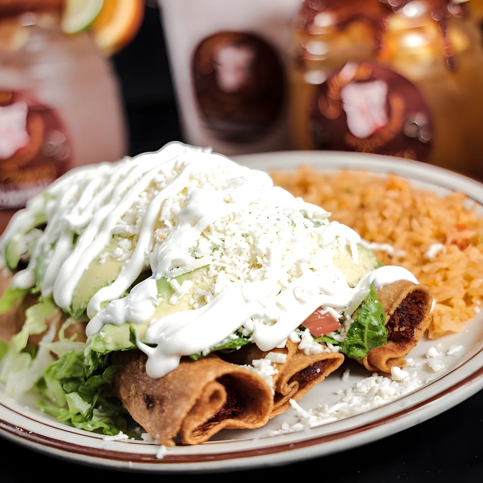 Los Chepes' taquitos with sour cream, avocado, lettuce, cheese, and a side of rice.