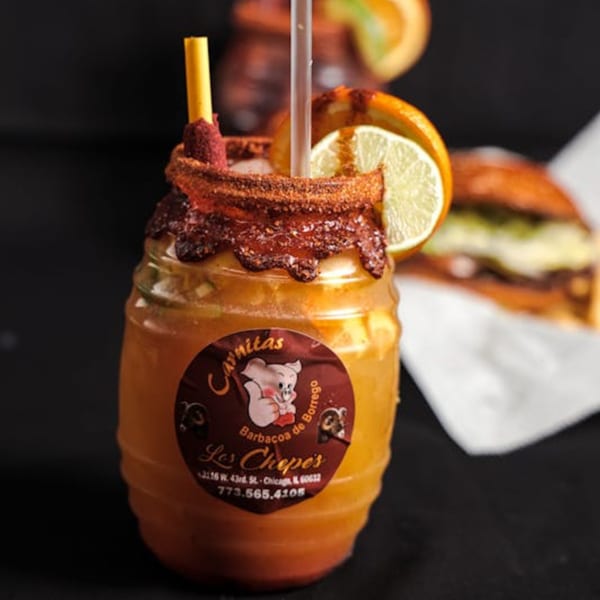 A Los Chepes Mexican drink in a barrel-shaped glass with chili rim, lime, and orange slices.